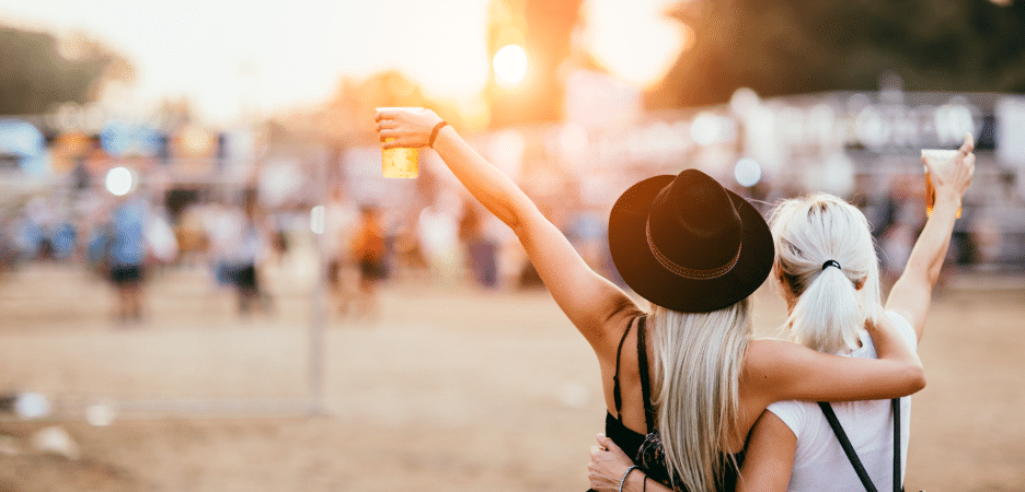 blond woman with black hat raising glass at a summer event in oklahoma