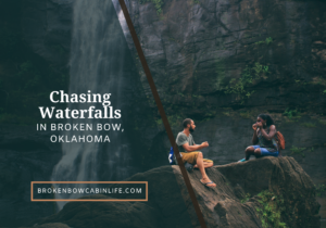 man and woman sitting on rock in front of waterfall